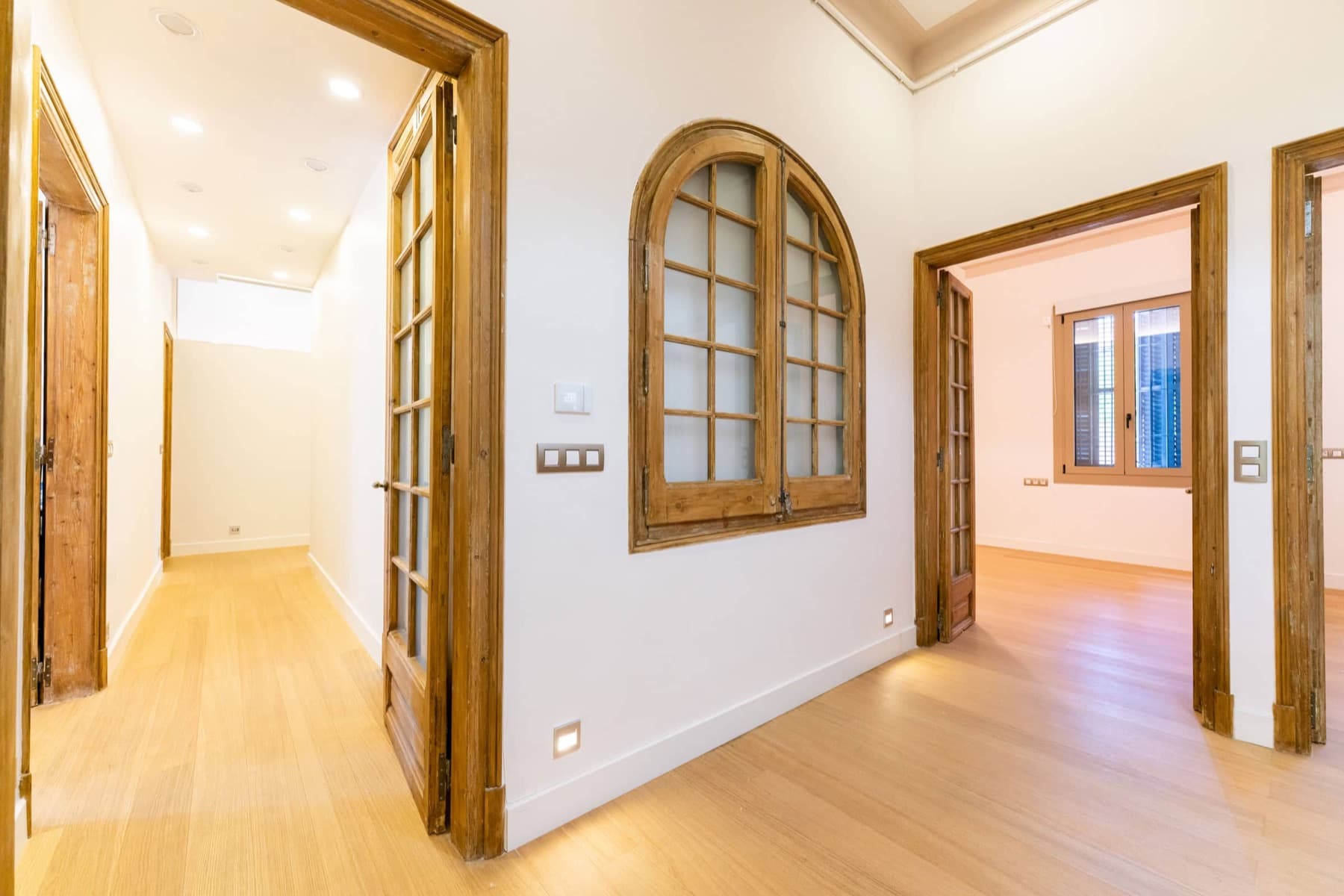 Recibidor de vivienda reformada en Barcelona con carpintería de madera restaurada
